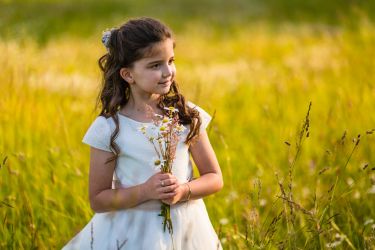 Reportaje de fotos de comunión de una niña en Miengo Cantabria, que está jugando con las flores
